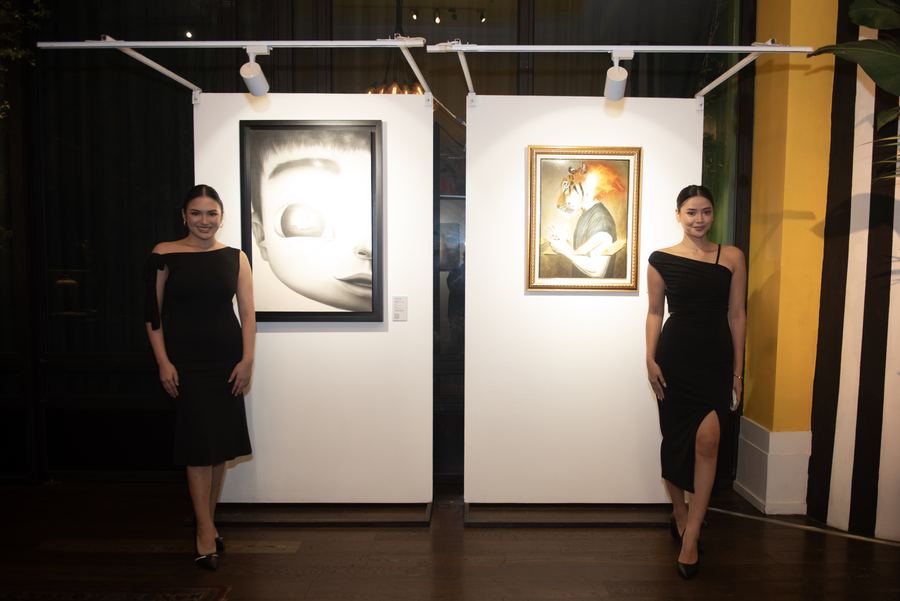Two presenters beside works on display